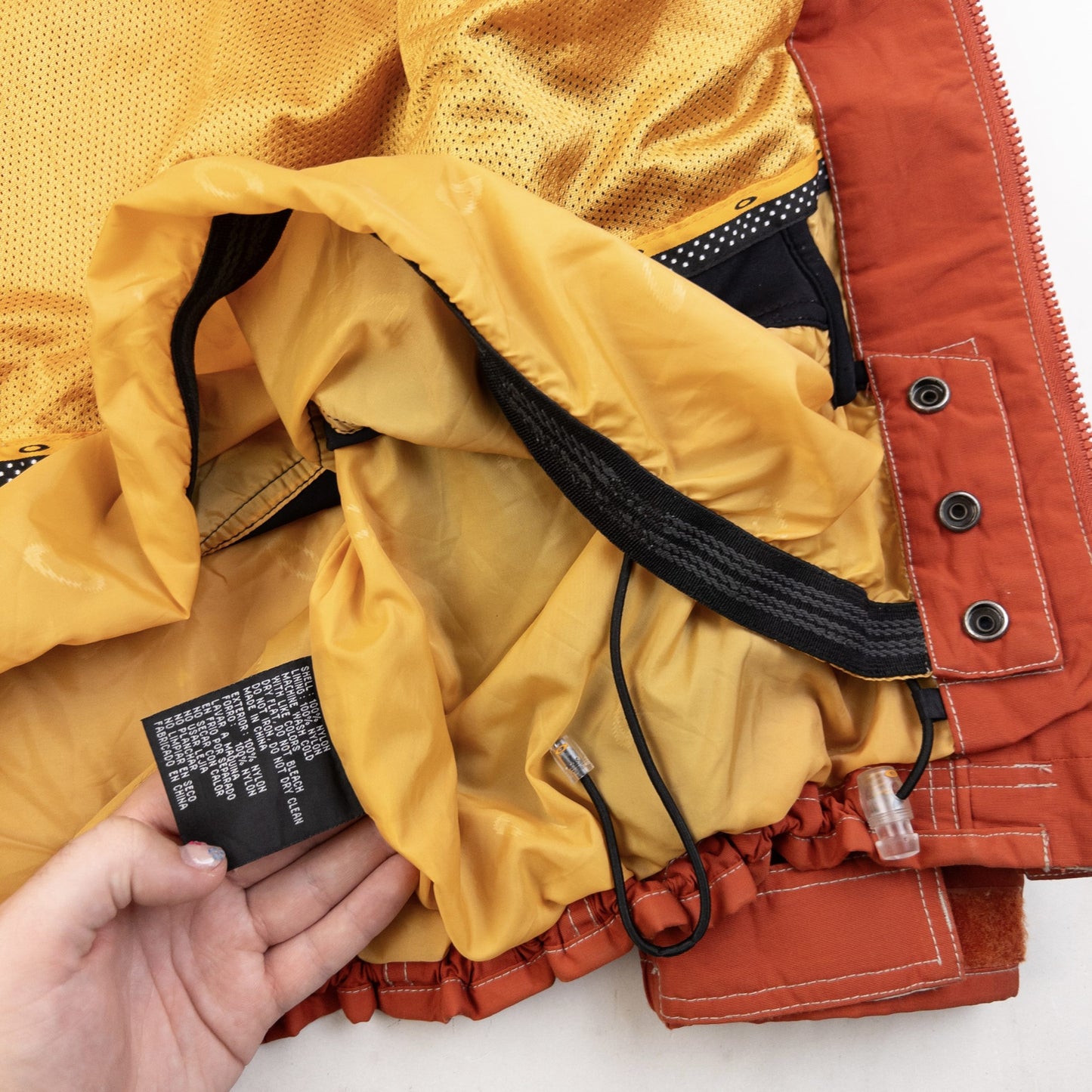 OAKLEY orange zip-up snowboarding jacket with reflective strip detail on chest and hood.