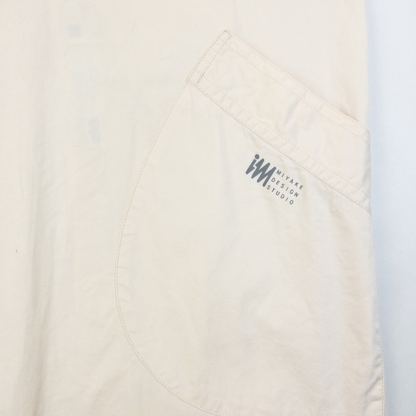 ISSEY MIYAKE beige apron with crossed back straps and stamped logo pocket detail