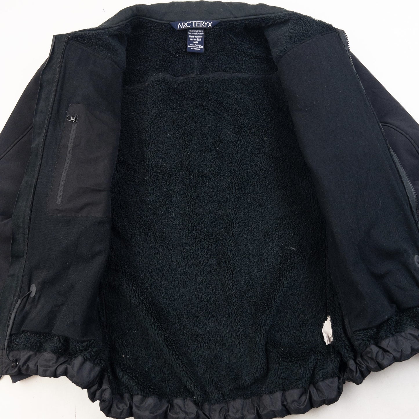 ARCTERYX black fleece jacket with embroidered logo on chest and zippered pockets.