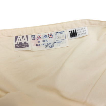 ISSEY MIYAKE beige apron with crossed back straps and stamped logo pocket detail