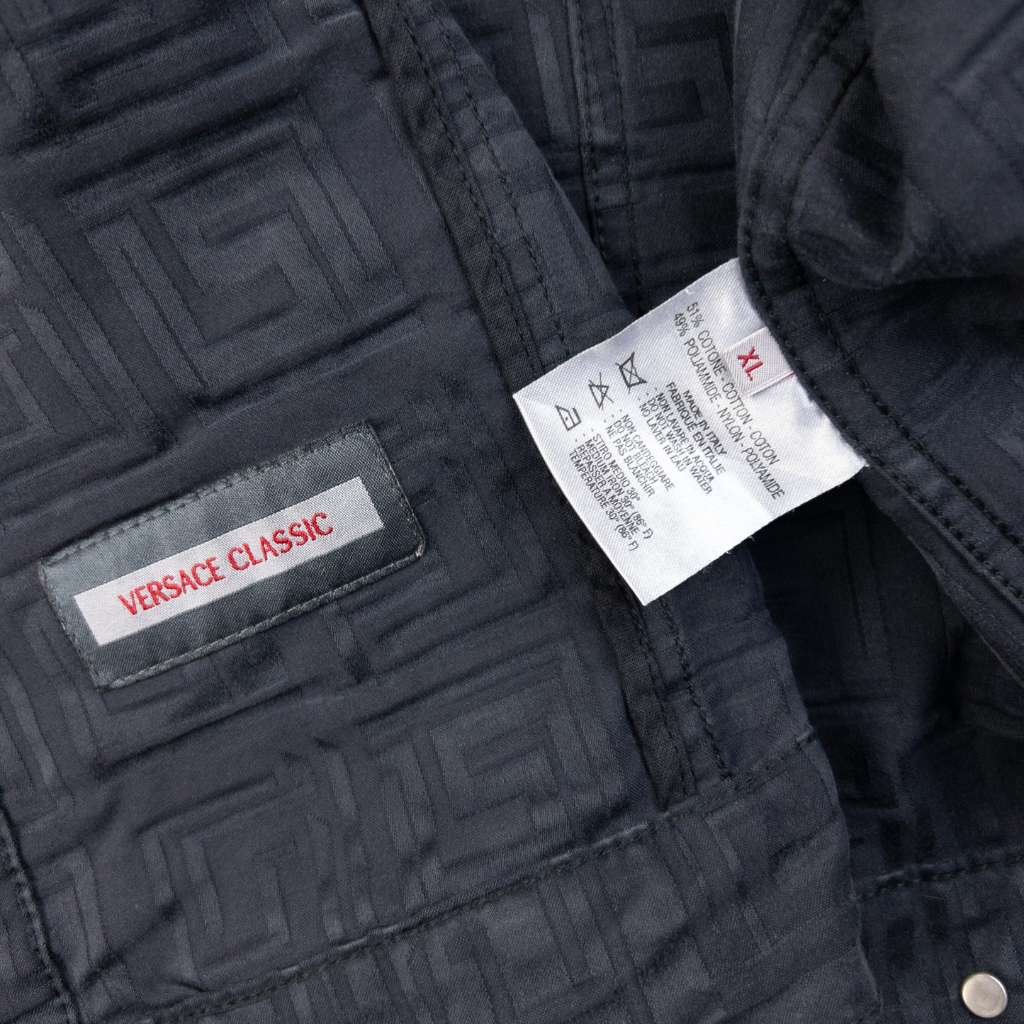 Versace Classic black button-up jacket embossed geometric pattern and branded metal buttons.